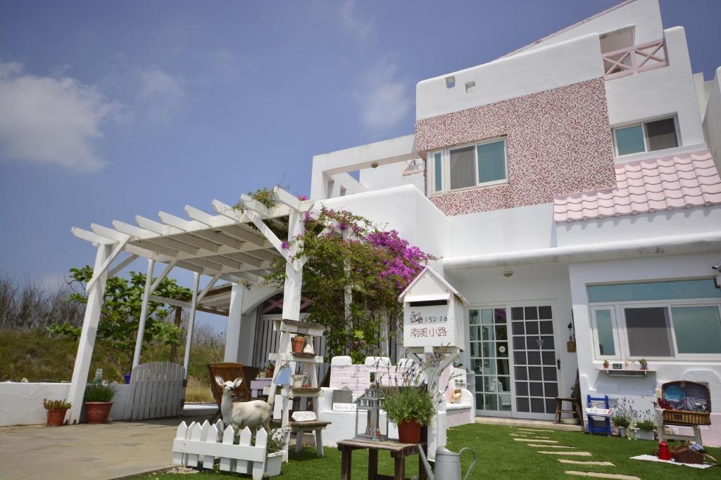 a white house with a garden in front of it at Minami Kaze in Magong