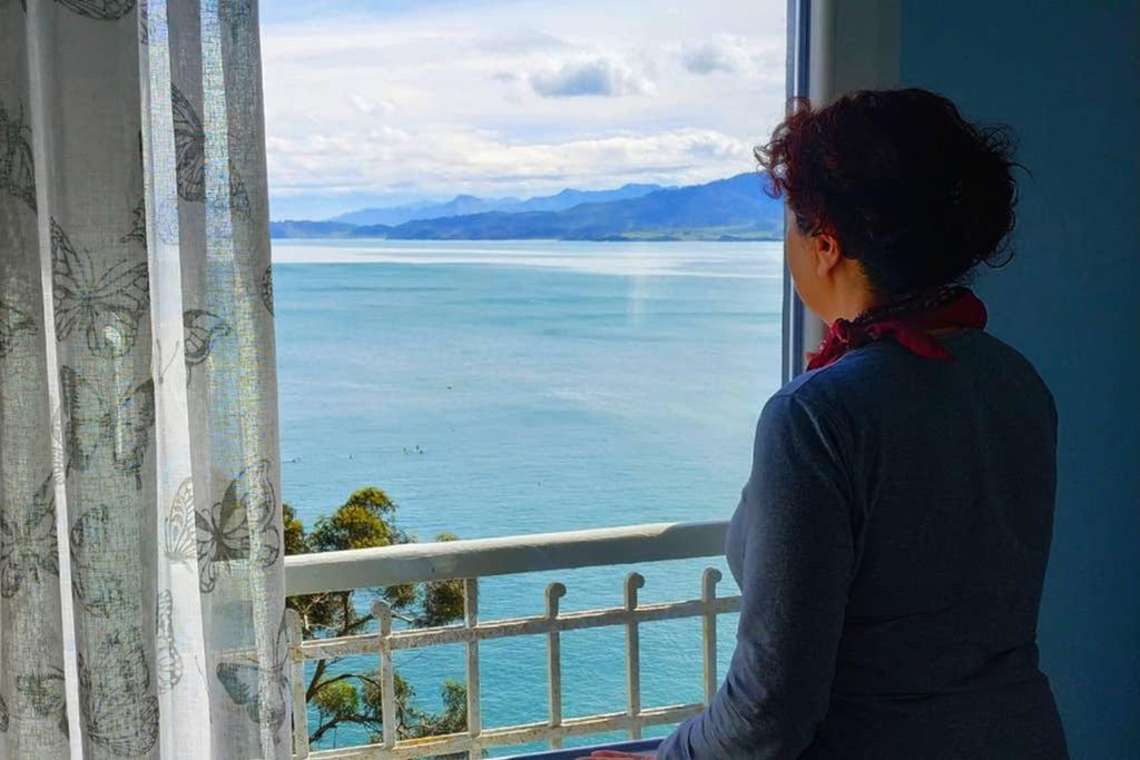Una mujer mirando por una ventana al océano en AlmenaraLove See Watching, en Lastres