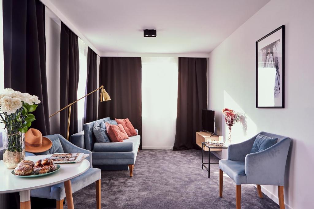 salon z kanapą, stołem i krzesłami w obiekcie Silesia Apartments w mieście Katowice