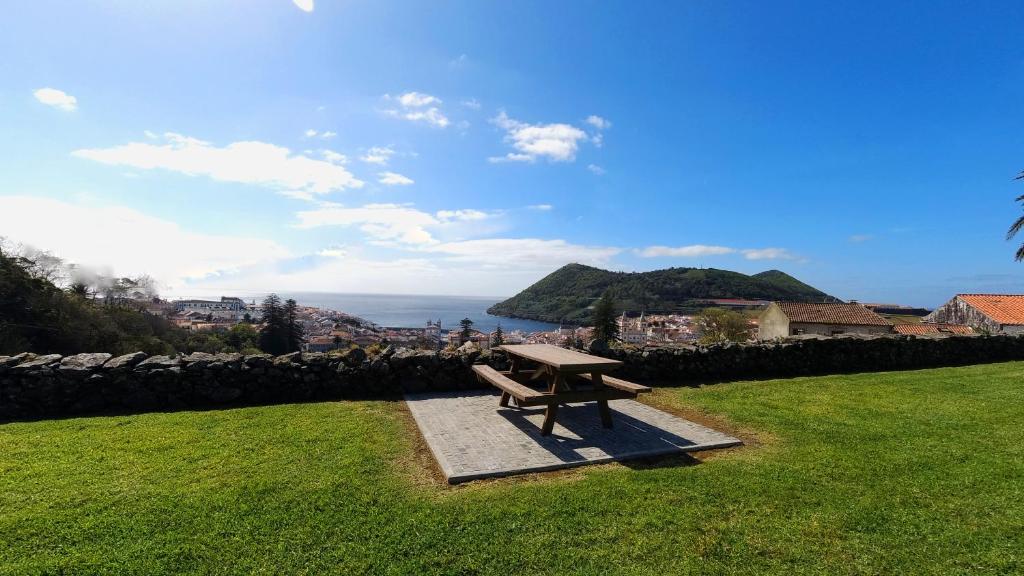 a bench sitting in the grass with a view of the ocean at Casa do Becco in Angra do Heroísmo