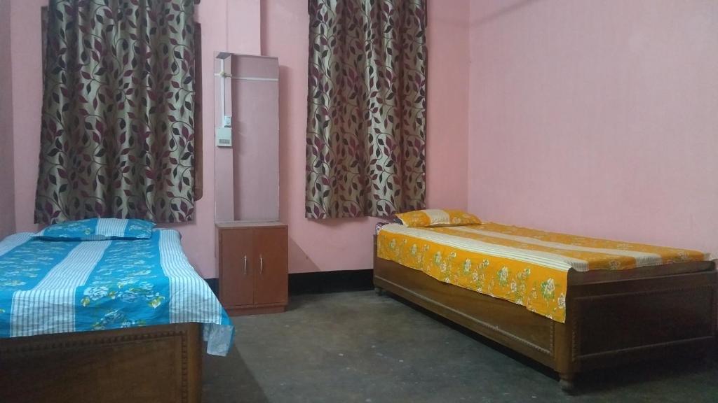 two beds in a room with pink walls and curtains at M B Holiday Home in Guwahati