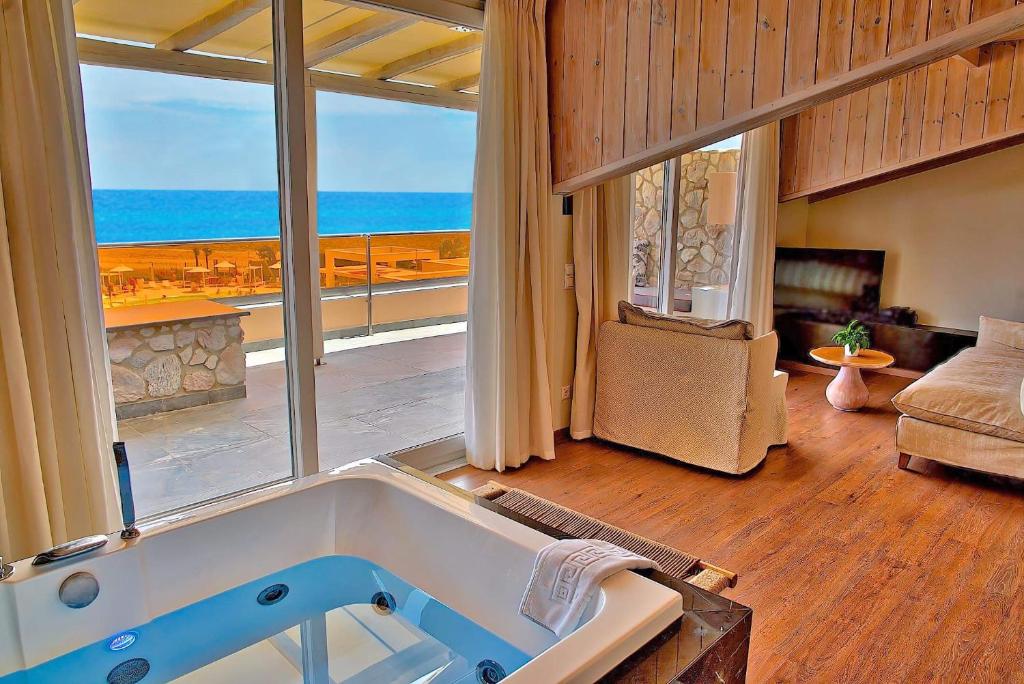 a bath tub in a room with a view of the ocean at Litohoro Olympus Resort Villas & Spa in Plaka Litochorou
