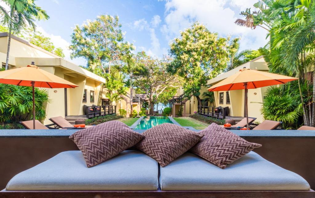 a bed in front of a pool with umbrellas at Villa Tanamera in Bang Rak Beach