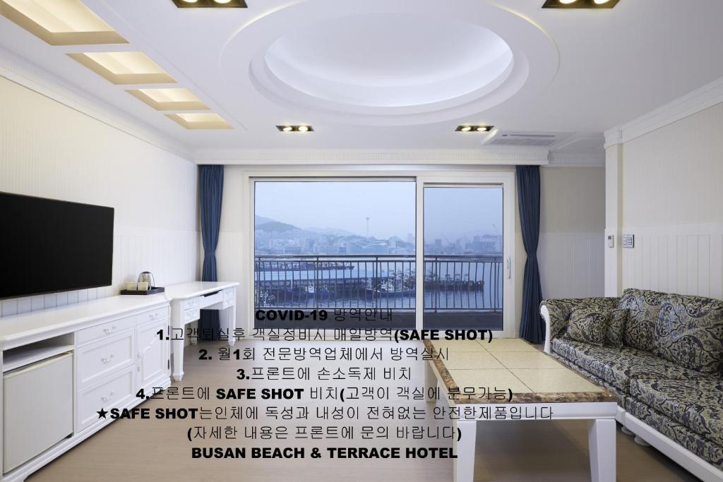 Busan Beach Hotel Busan Songdo في بوسان: غرفة معيشة بها أريكة وتلفزيون