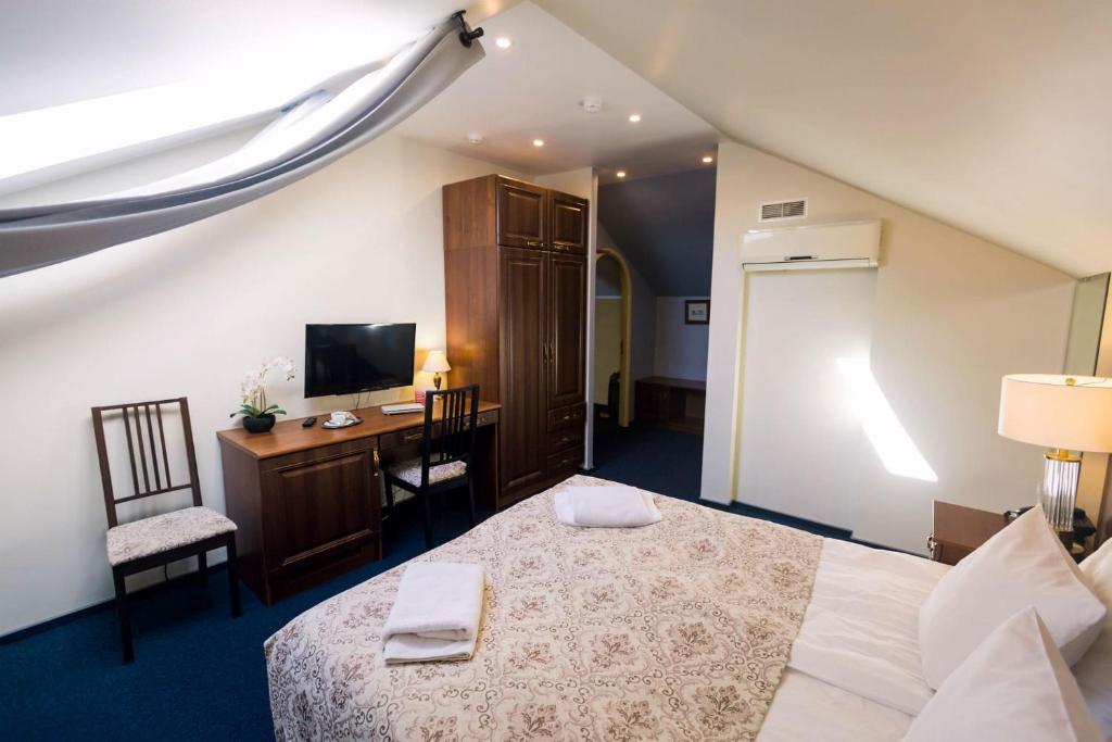 a bedroom with a bed and a desk and a television at History Hotel in Vologda
