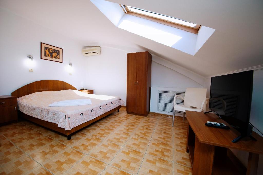 1 dormitorio con 1 cama y TV de pantalla plana en Yason Guest House, en Anapa