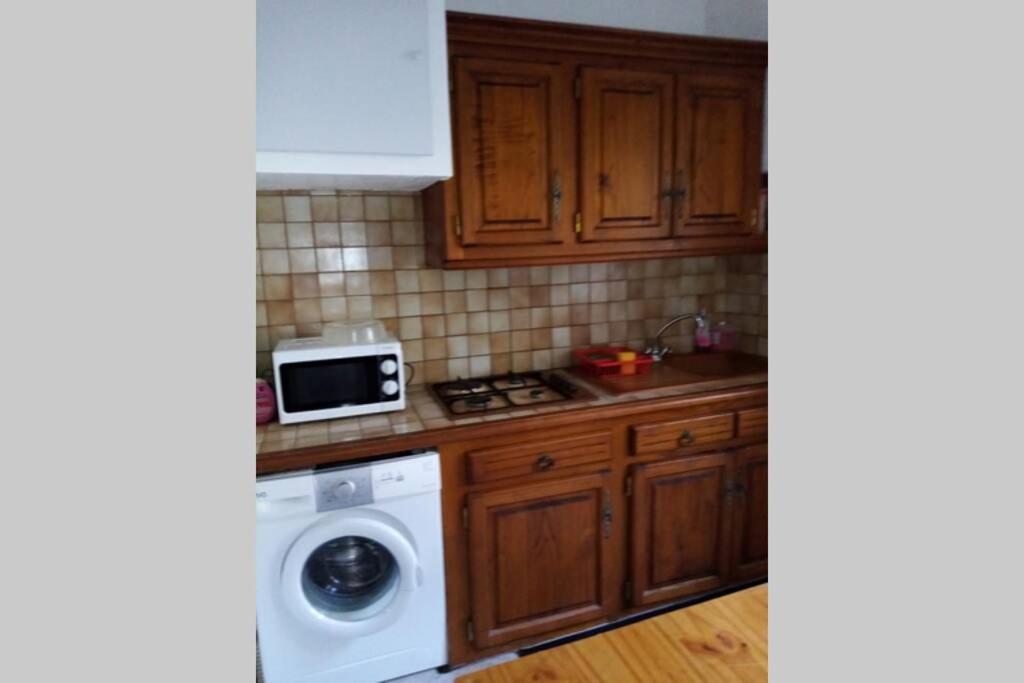 a kitchen with a washing machine and a microwave at Nid douillet in Vals-les-Bains