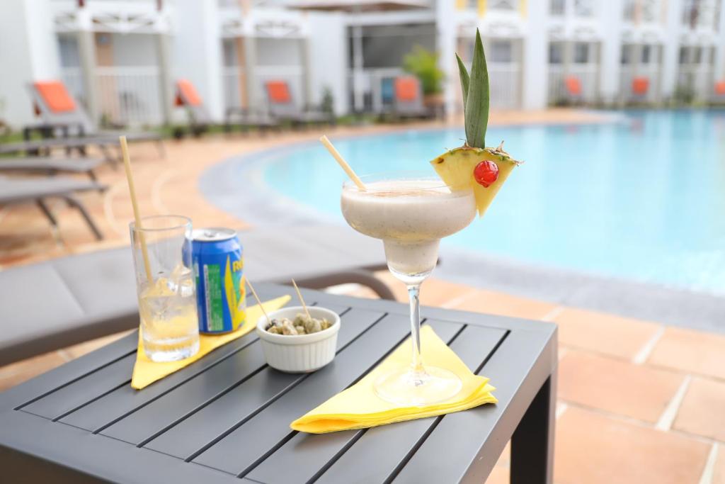 uma bebida sentada numa mesa ao lado de uma piscina em Hôtel Saint-Georges em Saint-Claude
