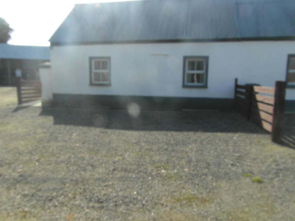 a white house with a black roof and a yard at Country Studio in Portarlington