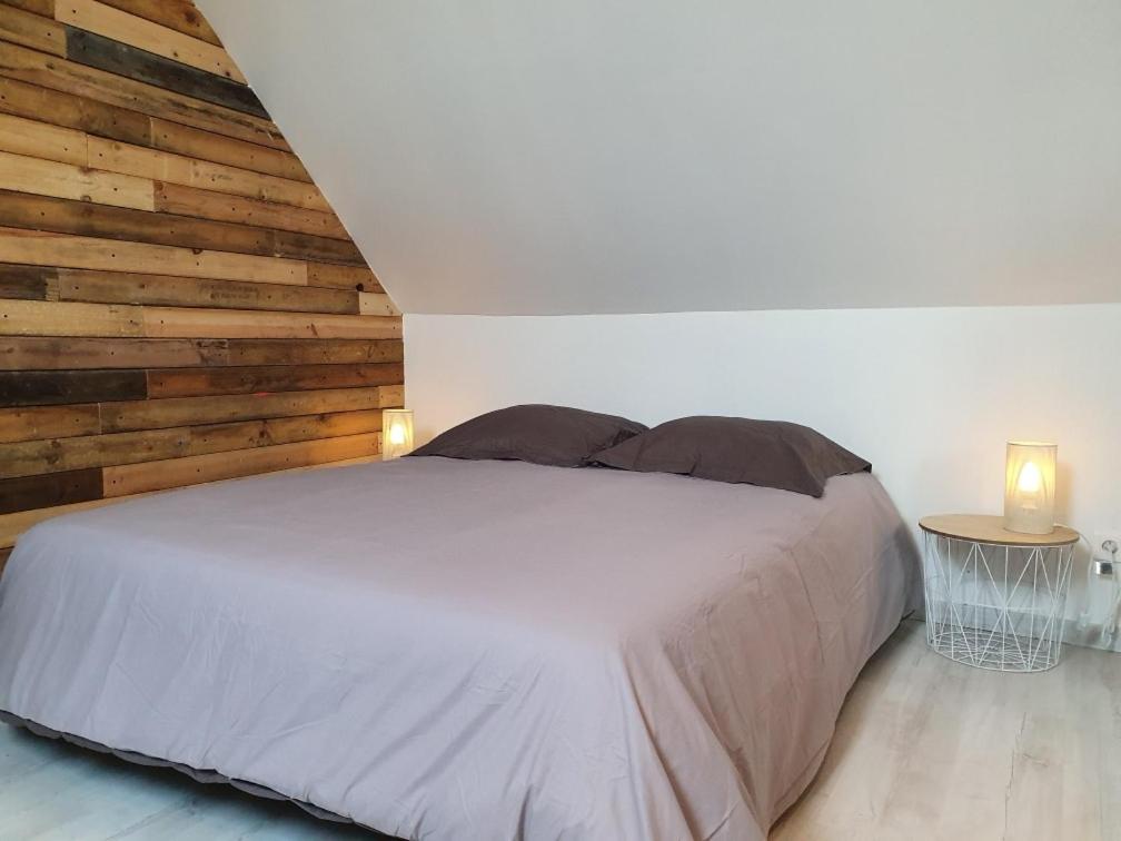 HébuterneにあるLe petit manoir d'Hebuterneの白いベッドと木製の壁が備わるベッドルーム1室が備わります。