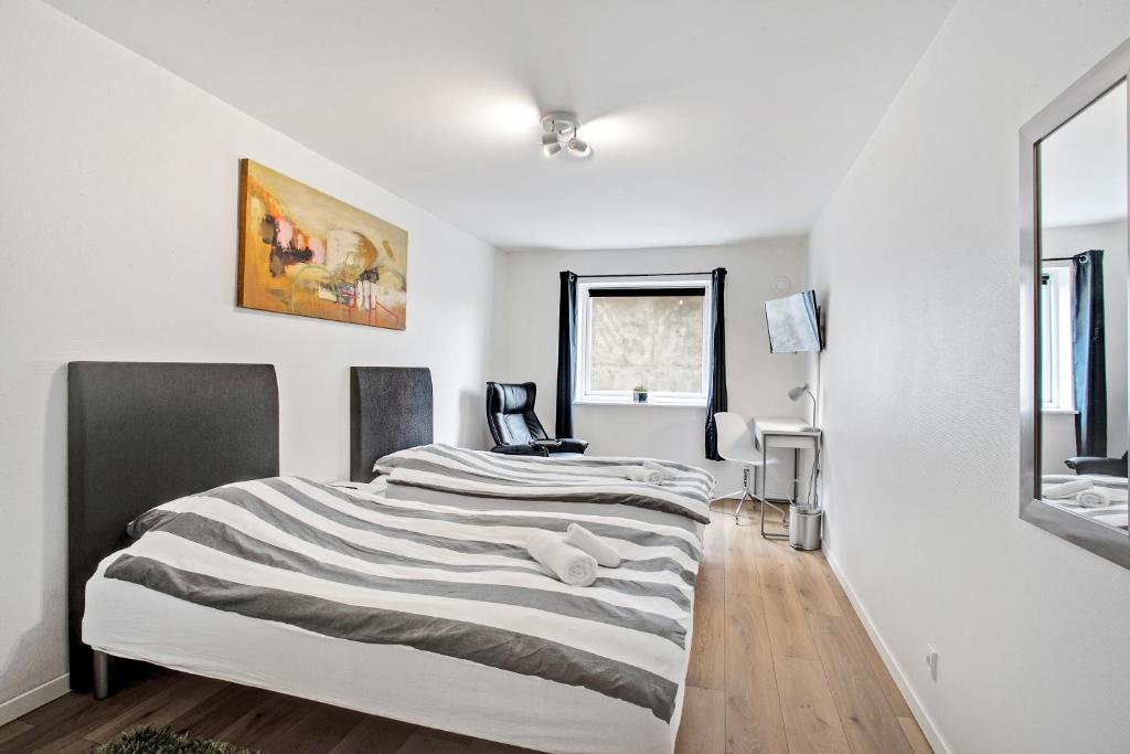 a bedroom with white walls and a striped bed at Just Sleep in Esbjerg