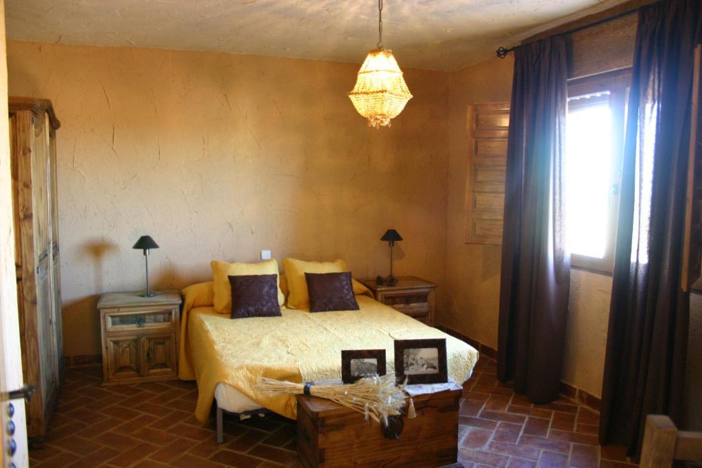 a bedroom with a bed and two tables and a window at Casa rural eras de pantrillar in Ciruelas