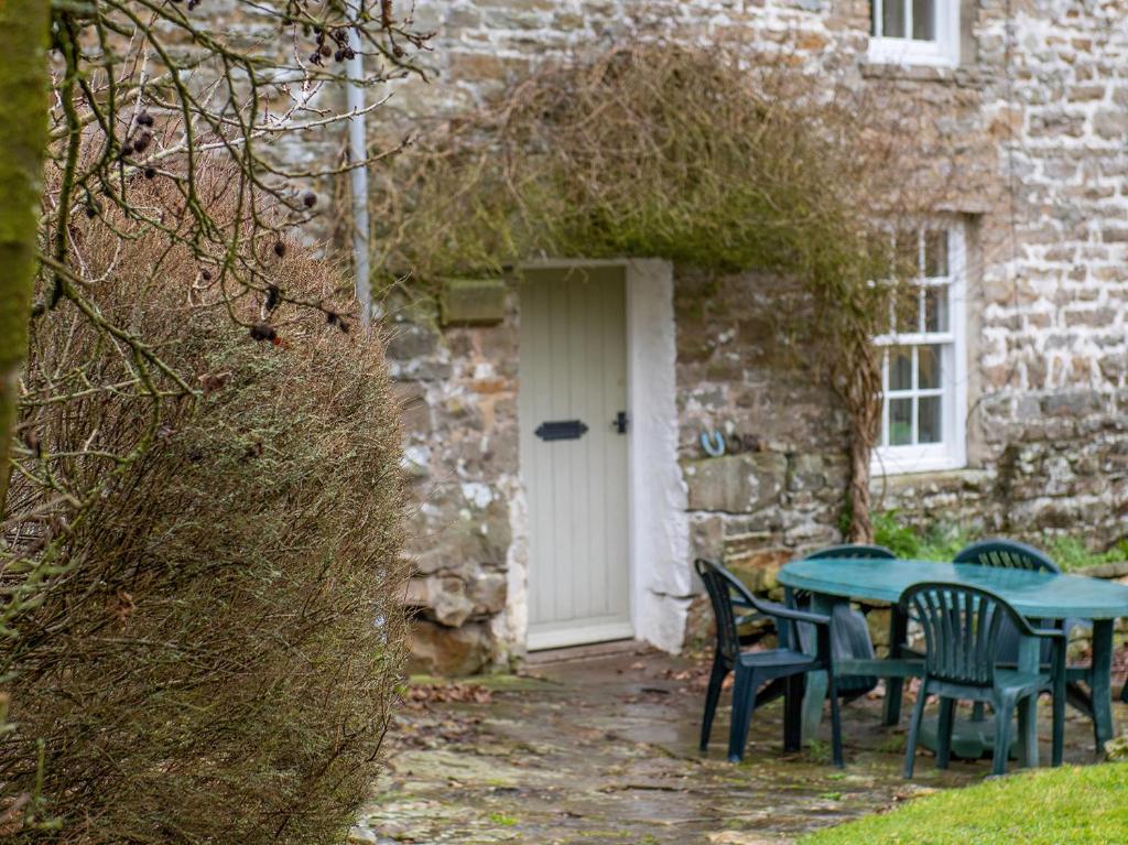 a table and chairs in front of a building with a white door at Joe House in Gunnerside