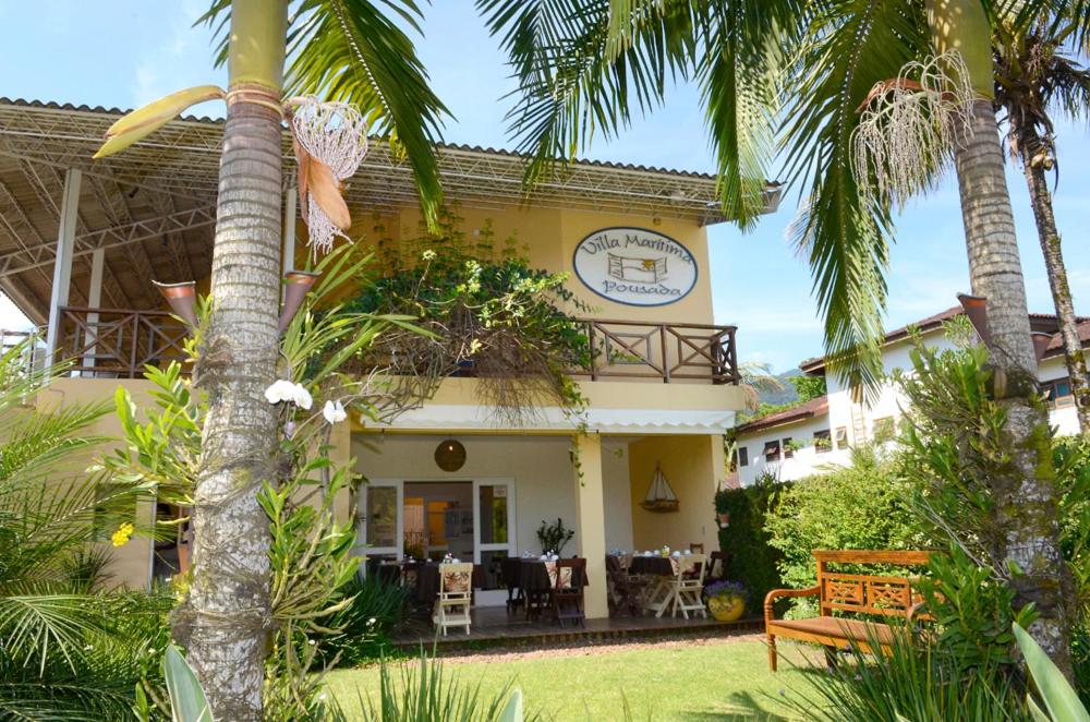 a house with palm trees in front of it at Pousada Villa Maritima in Juquei