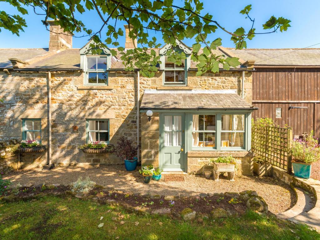 a stone house with a blue door and windows at Townfoot Cottage in Elsdon