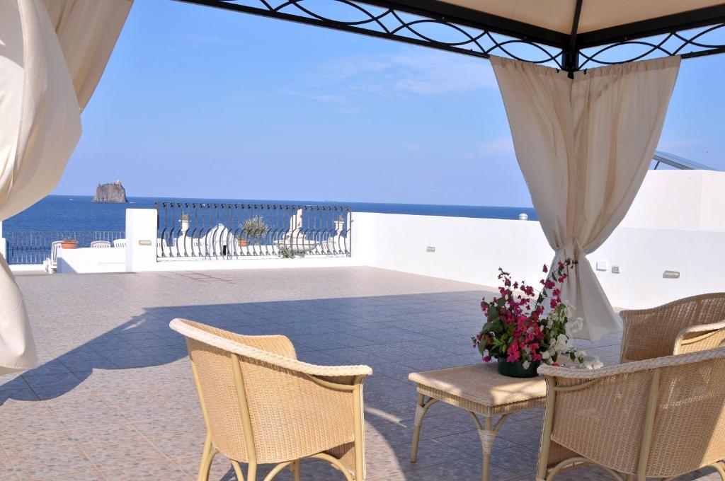 a patio with chairs and a table with flowers at Hotel Villaggio Stromboli - isola di Stromboli in Stromboli