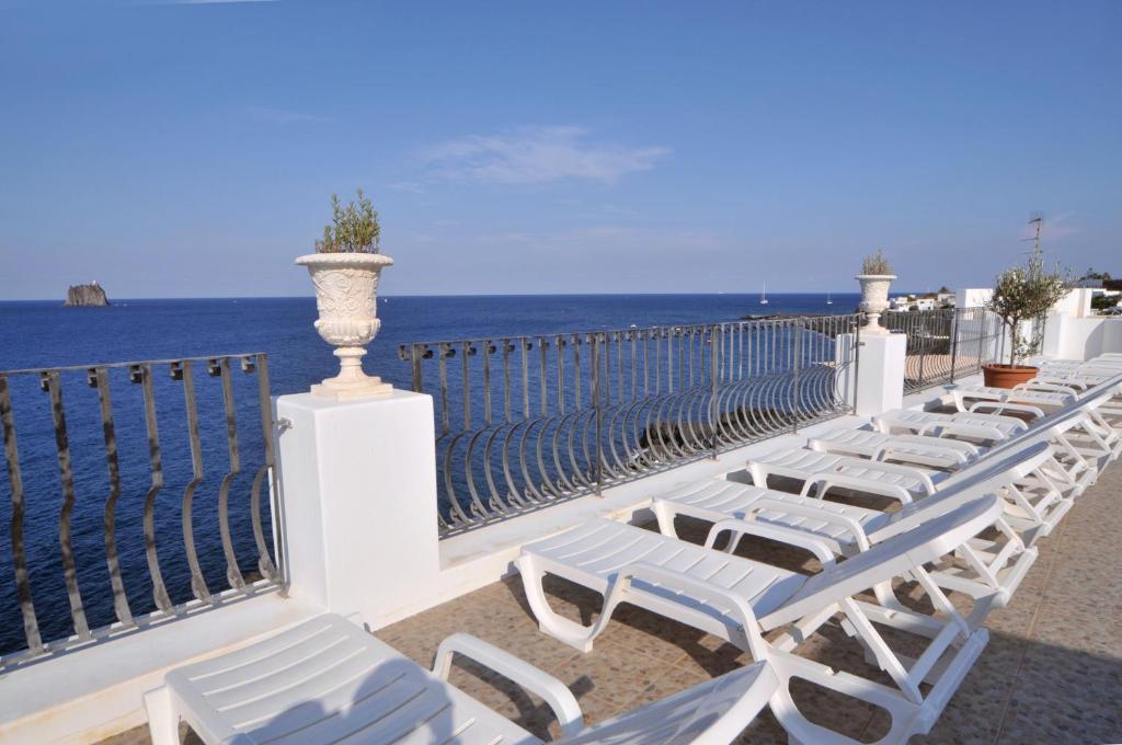 a row of white chairs on a balcony overlooking the ocean at Hotel Villaggio Stromboli - isola di Stromboli in Stromboli