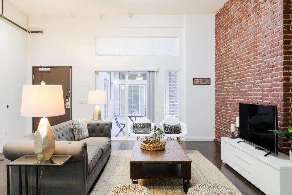 a living room with a couch and a brick wall at Abode Los Angeles - Downtown Historic Core in Los Angeles