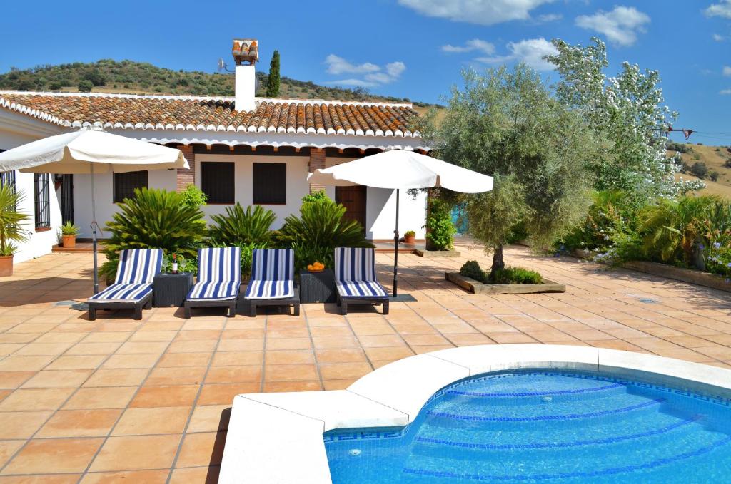 een villa met een zwembad en een huis bij Cortijo Cantares in Málaga
