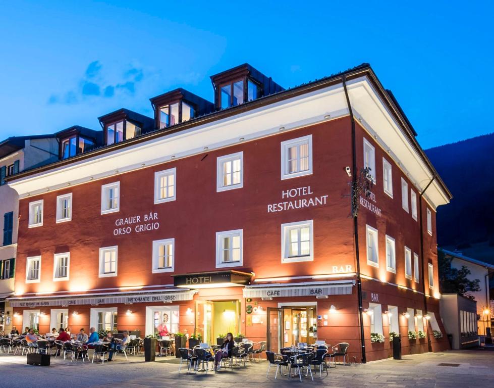 um hotel com mesas e cadeiras em frente a um edifício em Boutique & Gourmet Hotel Orso Grigio em San Candido