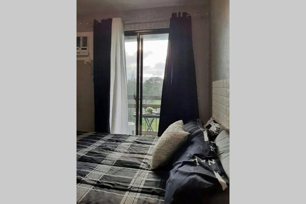een slaapkamer met een bed en een raam met uitzicht bij Pine Suites Tagaytay by StayPlus PH (Black and White Suite) FREE PARKING, CABLE TV, and WIFI in Tagaytay