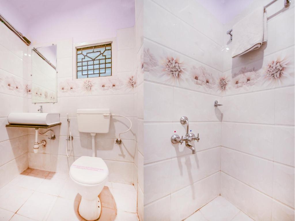 a white bathroom with a toilet and a shower at Aishwarya Le Royal in Mysore
