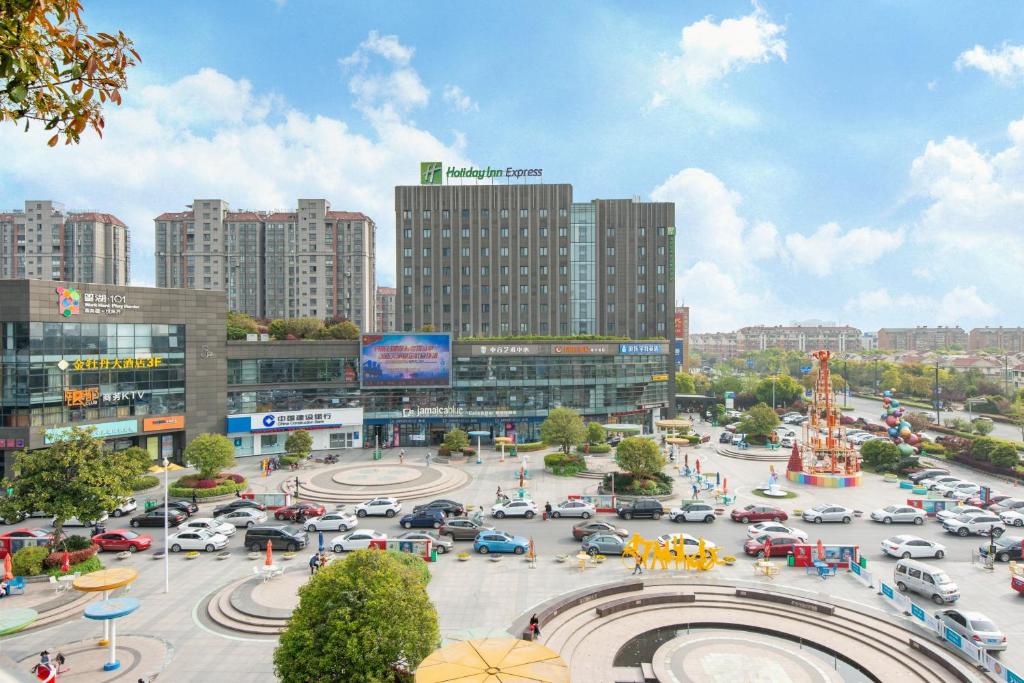 a busy city with cars parked in a parking lot at Holiday Inn Express Nantong Xinghu by IHG in Nantong