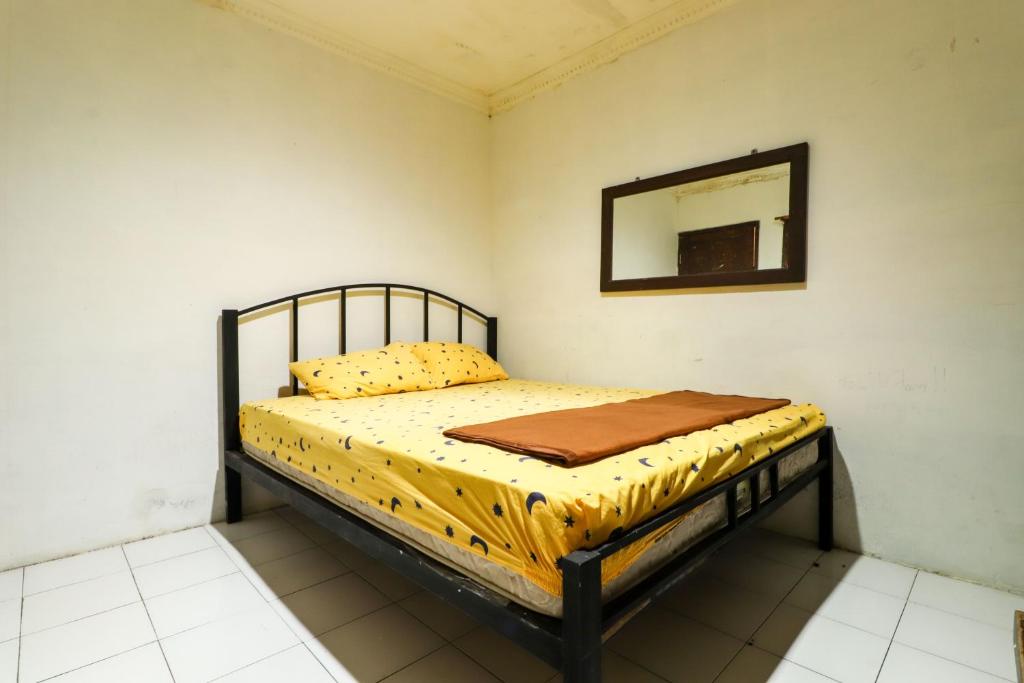 een bed in een kamer met een spiegel aan de muur bij Kos VIP Josh in Yogyakarta