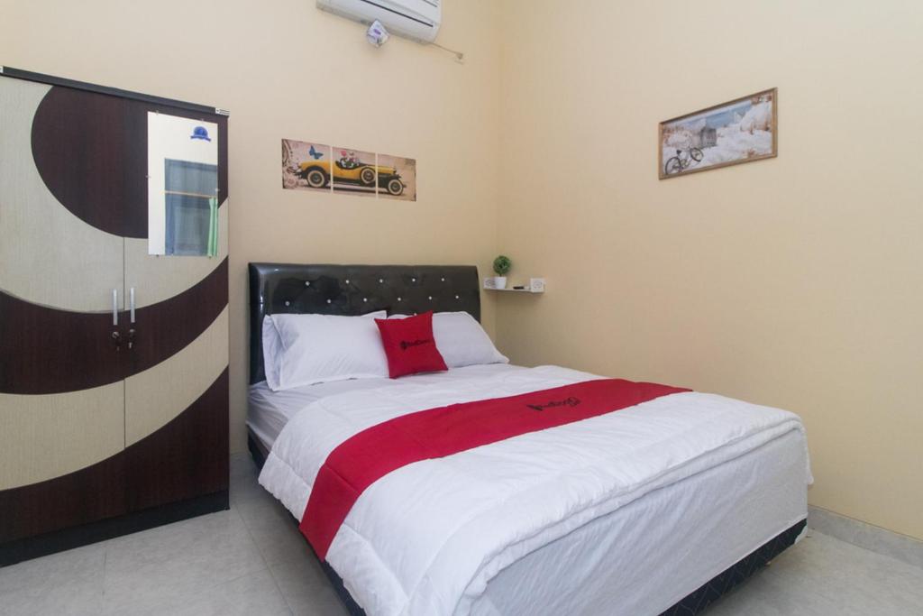 Schlafzimmer mit einem Bett mit einer roten und weißen Decke in der Unterkunft RedDoorz Syariah near Stasiun Madiun in Madiun