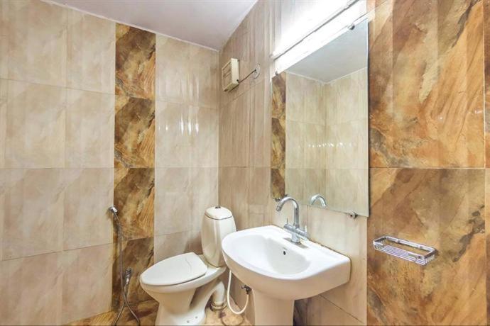 ein Badezimmer mit einem Waschbecken, einem WC und einem Spiegel in der Unterkunft Hotel Jaya International in Hyderabad