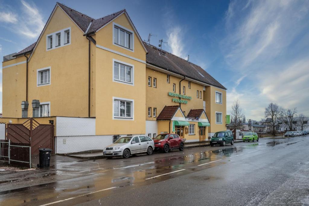 un gran edificio amarillo con coches aparcados en un aparcamiento en Hotel U Mydlářů, en Mnichovo Hradiště