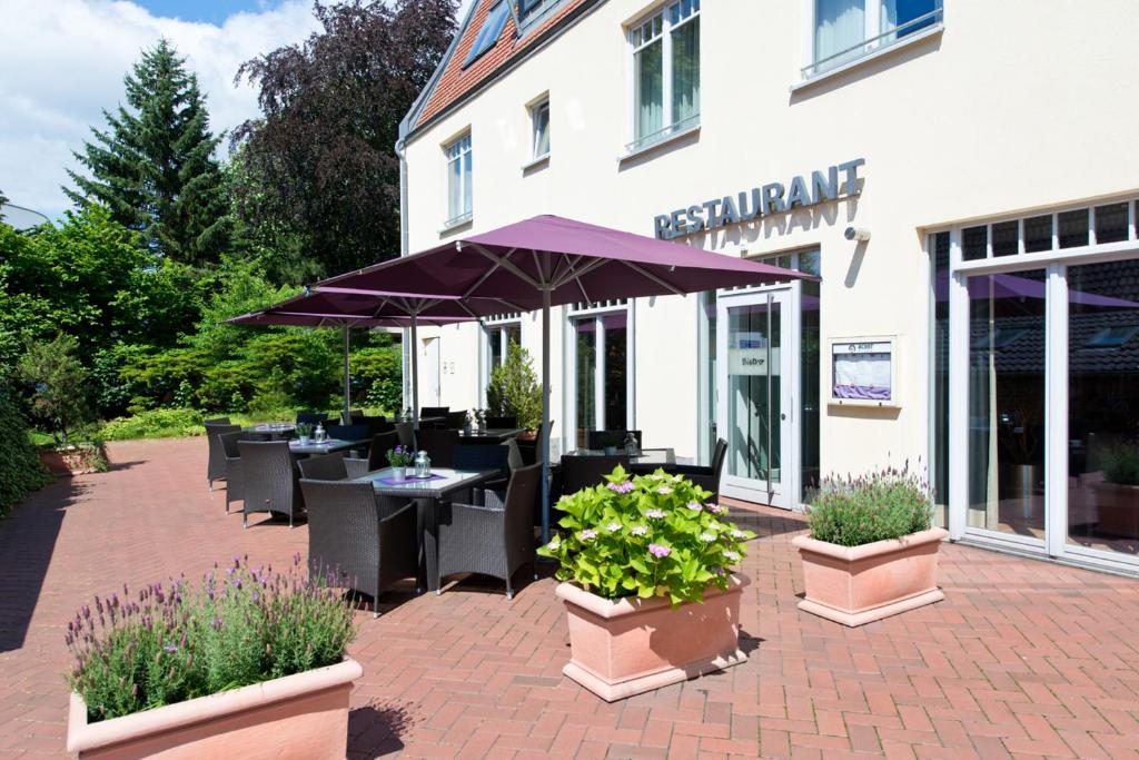 a patio with tables and chairs and purple umbrellas at ACHAT Hotel Buchholz Hamburg in Buchholz in der Nordheide
