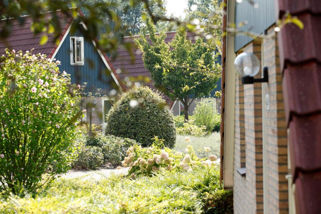 um jardim com arbustos e flores em frente a uma casa em Vakantie bij Meeussen - Molendal em Plasmolen