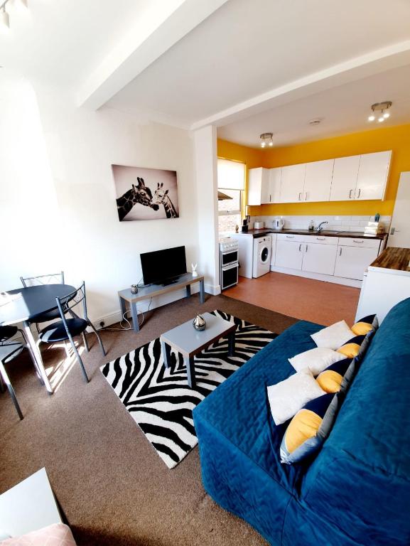 ein Wohnzimmer mit einem blauen Sofa und einer Küche in der Unterkunft Three Bedroom Apartment In Heart Of Rayleigh in Rayleigh