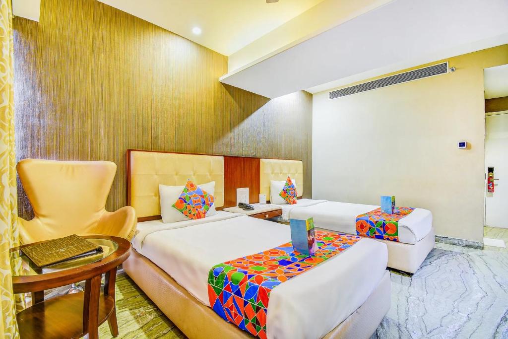 Cette chambre comprend deux lits, une table et une chaise. dans l'établissement The Hotel Orient Taibah, à Nagpur