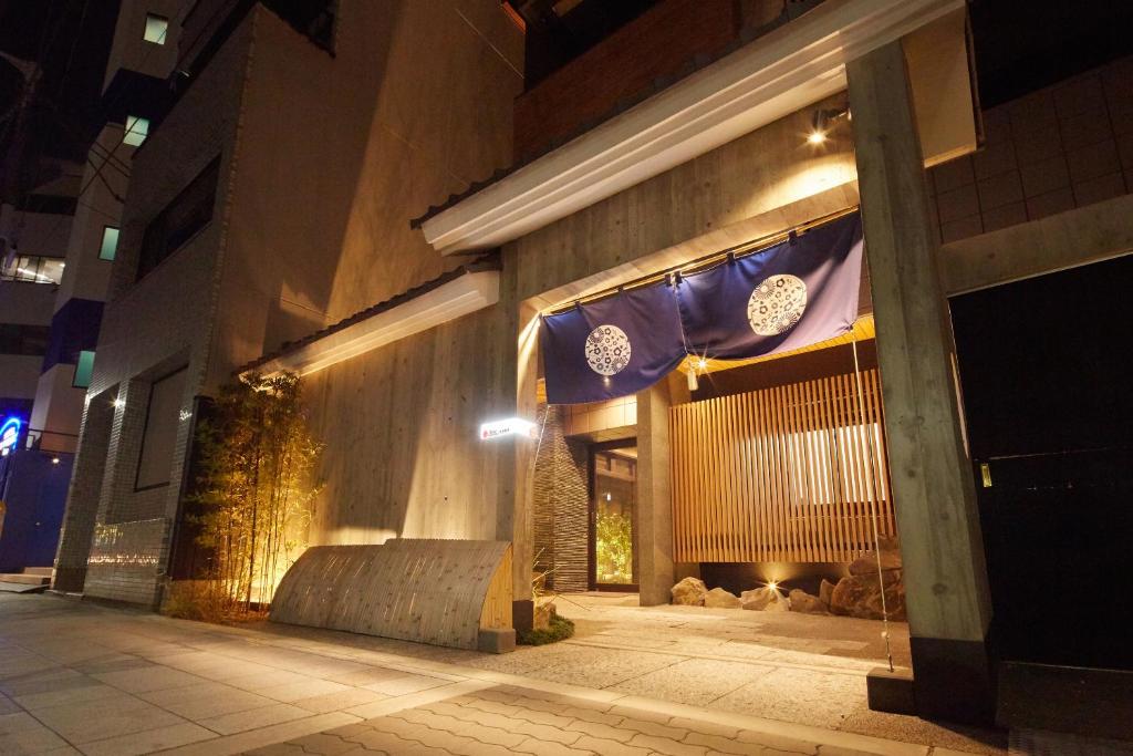 a building with flags on the side of it at night at Hotel Amaterrace Nippombashi-higashi in Osaka
