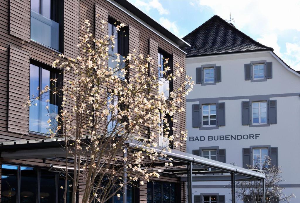 Bad Bubendorf Design & Lifestyle Hotel في Bubendorf: مبنى امامه شجرة