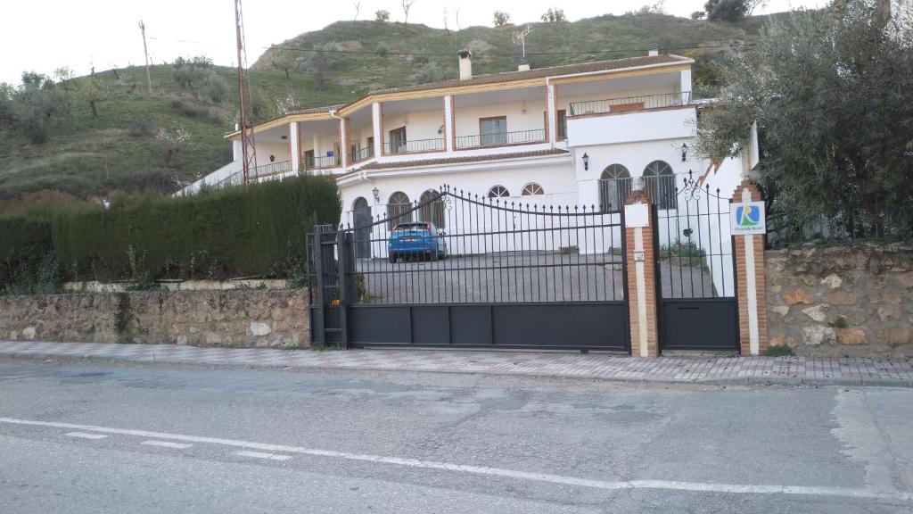 a large white house with a black gate at Alojamiento Árdales in Frailes