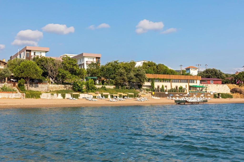 a beach with chairs and buildings and the water at Troas Beach Hotel in Tavaklı