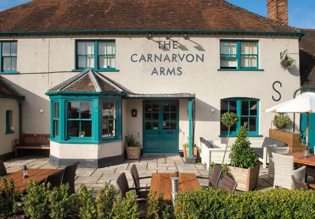 un edificio con sillas y mesas delante de él en The Carnarvon Arms en Newbury