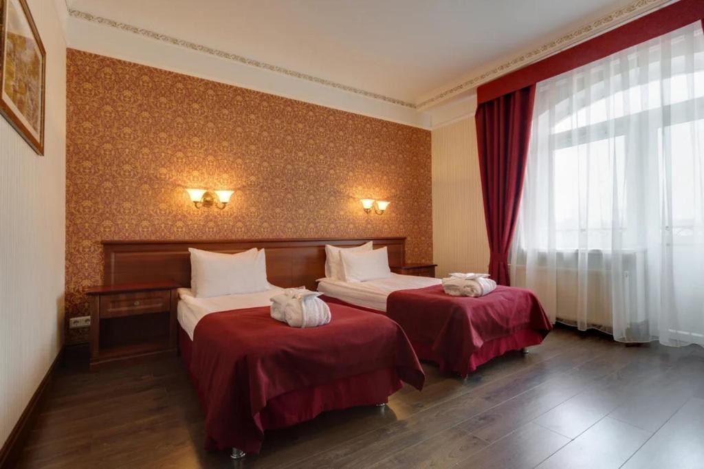 a hotel room with two beds with red sheets at Grand Peterhof Spa Hotel in Petergof