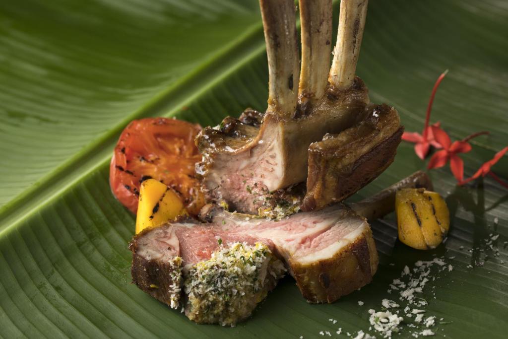 a piece of meat with a fork on a green leaf at Sheraton Okinawa Sunmarina Resort in Onna