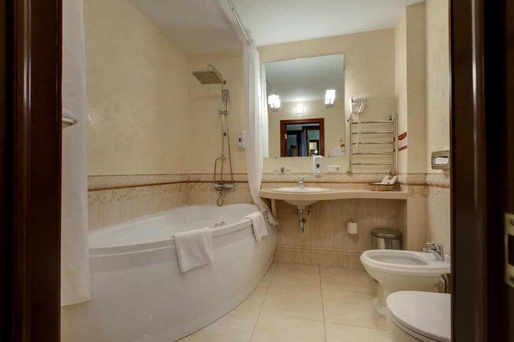 a bathroom with a tub and a sink and a toilet at Grand Peterhof Spa Hotel in Petergof