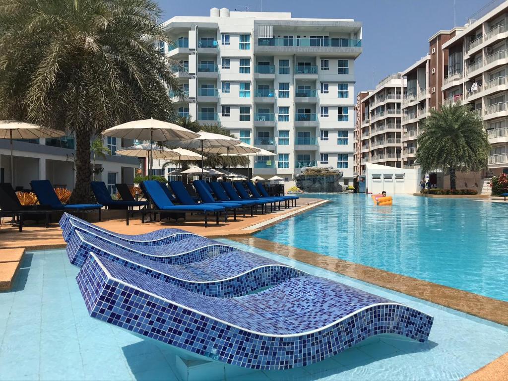 una piscina con sillas azules y un edificio en GrandBlue Condominium Mae Phim TOP FLOOR WITH SEA VIEW 706, en Mae Pim
