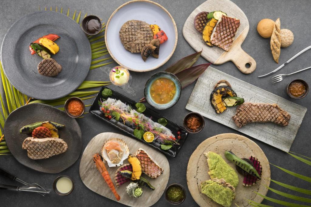 a table topped with plates of food and bowls of dips at Sheraton Okinawa Sunmarina Resort in Onna