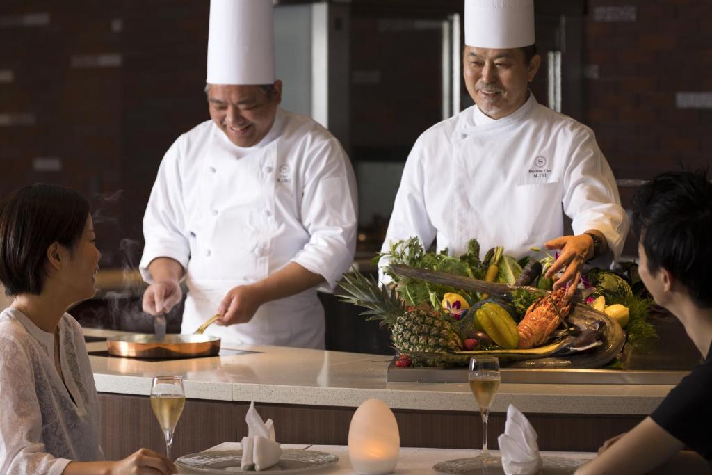 a chef preparing food in a kitchen with a group of people at Sheraton Okinawa Sunmarina Resort in Onna