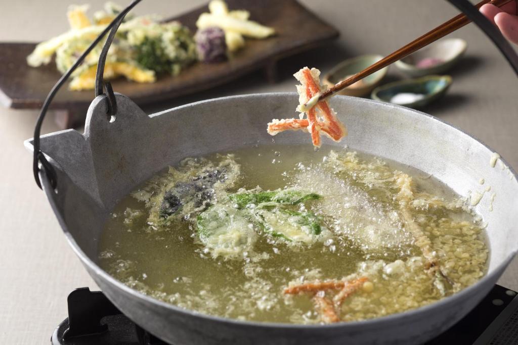 a person is stirring a bowl of soup with chopsticks at Sheraton Okinawa Sunmarina Resort in Onna