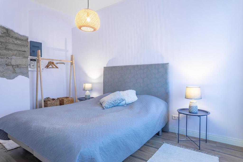 1 dormitorio con 1 cama azul, 2 mesas y 2 lámparas en Südalinna apartment, en Kuressaare