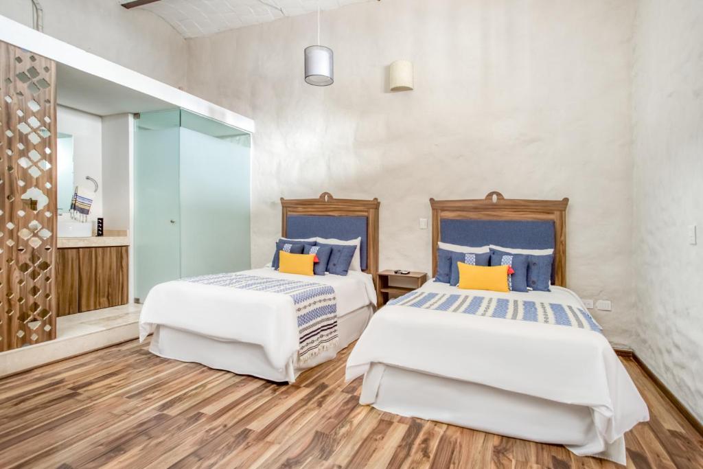 two beds in a room with wood floors and white walls at Hotel Milagro, Puebla Centro in Puebla