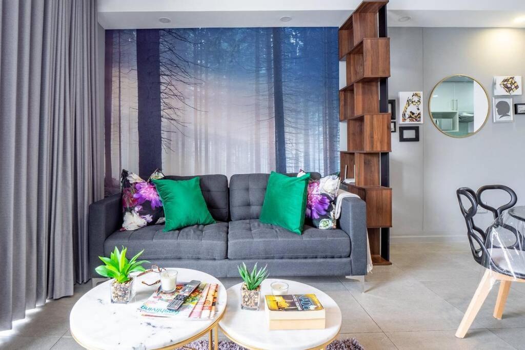 uma sala de estar com um sofá cinzento e almofadas verdes em Inner Harbour Charm em Durban